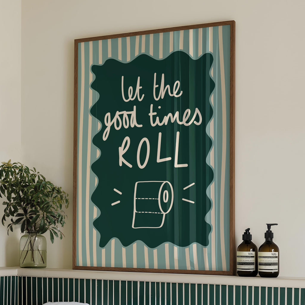 Bathroom with a framed quote 'let the good times roll' above a bathtub, featuring green tiles and towels.