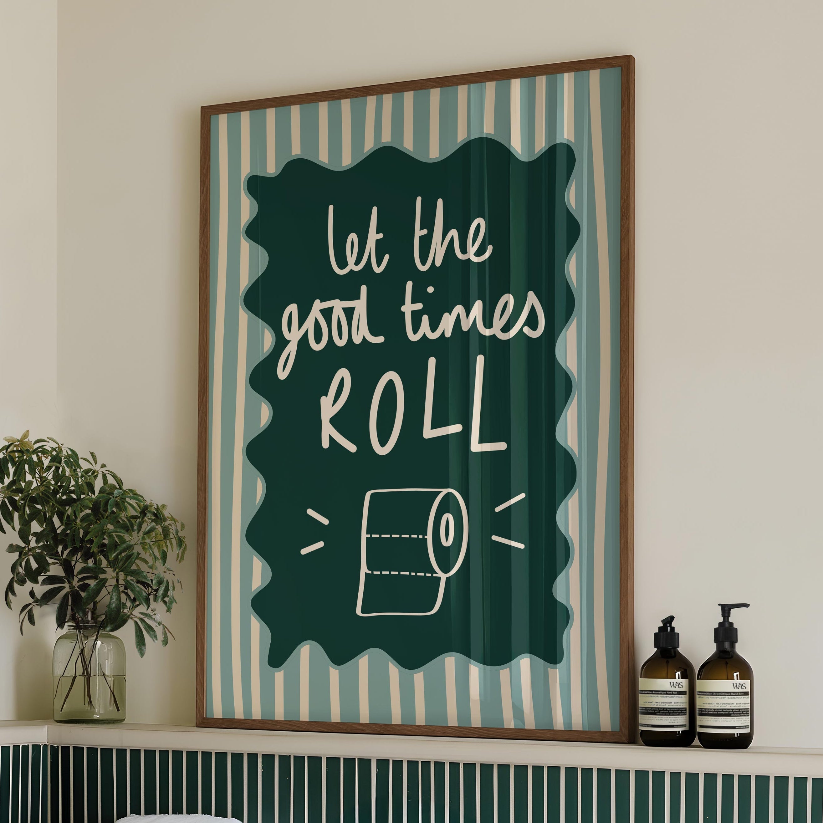 Bathroom with a framed quote 'let the good times roll' above a bathtub, featuring green tiles and towels.